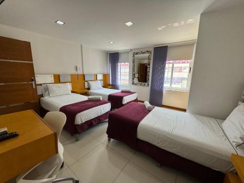 a hotel room with two beds and a desk at HOTEL SAN ANTONIO PLAZA in Cali