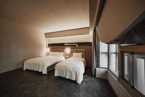 two beds in a hotel room with white sheets at Hub Hotel Kaohsiung Yisin Branch in Kaohsiung
