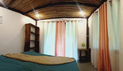 een slaapkamer met een bed en een aantal gordijnen bij Paradise Surf in Dapa