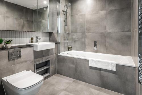 a bathroom with a toilet and a sink and a tub at Urban Rest Stratford Apartments in London