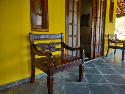 a wooden bench in a room with a yellow wall at Sítio Bosque das Palmeiras in Papucaia