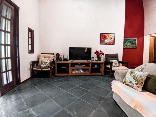 a living room with a couch and a television at Sítio Bosque das Palmeiras in Papucaia