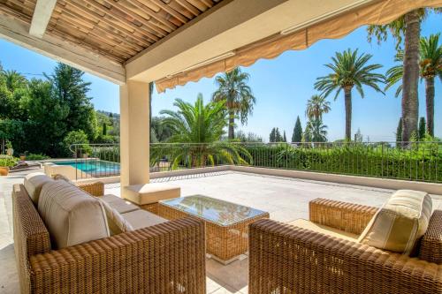 un patio extérieur avec des chaises en osier et une table dans l'établissement Cannes Luxury Rental - Stunning 5 bedroom villa to rent, à Cannes