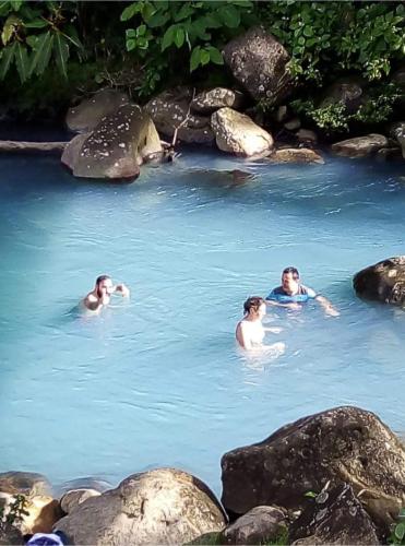 a group of people swimming in a pool of water at Cabinas El Pilón Río Celeste in San Rafael