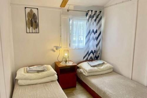 2 Einzelbetten in einem kleinen Zimmer mit Fenster in der Unterkunft Holiday cottages, sauna, whirlpool, Mrze yno in Mrzeżyno