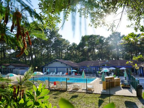 - une piscine avec des chaises et des parasols en face d'une maison dans l'établissement Holiday Home in France near Atlantic Beach, à Moliets-et-Maa