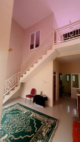 een woonkamer met een trap en een rode stoel bij NK Villa Syariah Batu in Batu