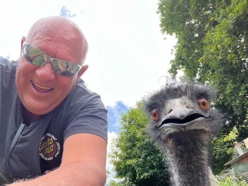 a man in sunglasses is next to an ostrich at 4 Winds Farm Homestay in Jumbuk