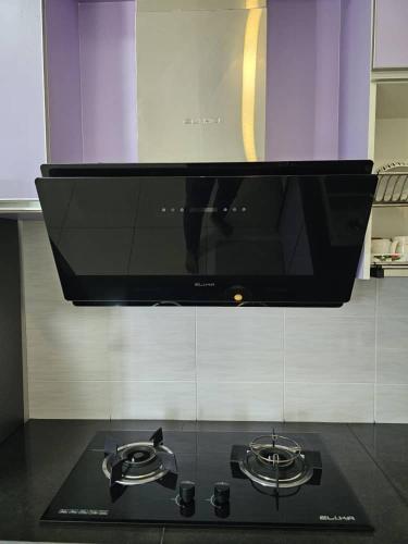 a black stove top with a microwave above it at A&H Homestay Seberang Jaya with Swimming Pool & 3 Bedroom AC in Permatang Janggus