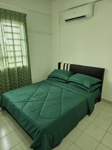 a bed with a green comforter in a bedroom at A&H Homestay Seberang Jaya with Swimming Pool & 3 Bedroom AC in Permatang Janggus