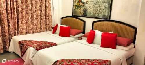 duas camas num quarto de hotel com almofadas vermelhas em Forest Paradise Inn Teluk Bahang PRIVATE MALAY TRADITIONAL HOUSE CONCEPT HOTEL em Teluk Bahang