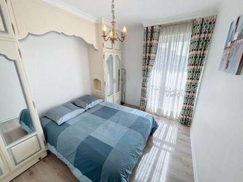 - une chambre avec un lit bleu et un lustre dans l'établissement Appartement au centre de Granville avec garage privatif et Wi-Fi gratuite - FR-1-361-510, à Granville