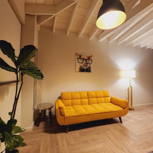 um sofá amarelo numa sala de estar com uma planta em Private Home Studio Central Located in Miami 1 em Opa-locka
