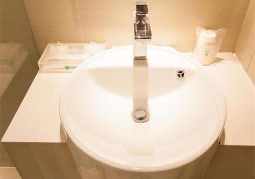 La salle de bains est pourvue d'un lavabo blanc et d'un robinet. dans l'établissement City Comfort Inn Nanning Chaoyang Parkson Pedestrian Street, à Nanning