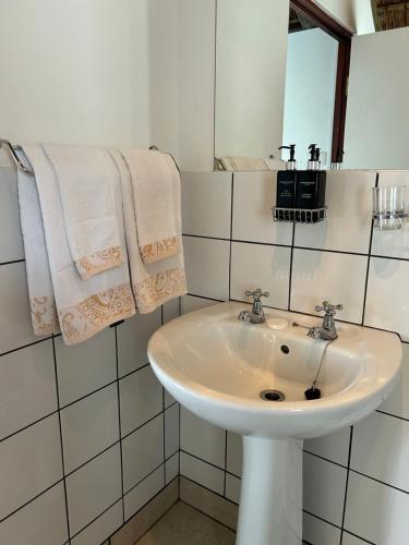 a white bathroom with a sink and towels at Tree Aloe Guest house in St Francis Bay