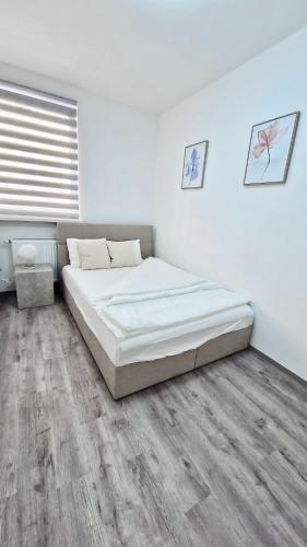 a white bedroom with a bed and a wooden floor at Central Cute City Apartment w Free Parking in Ljubljana