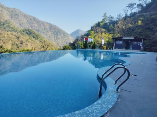 a pool with blue water and mountains in the background at HOA Resorts - Mountain View with Infinity Pool in Shivpuri