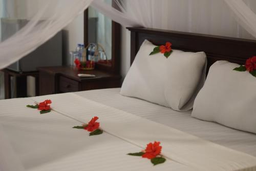 a white bed with red flowers on top of it at Turtle Bay Beach Resort in Mirissa
