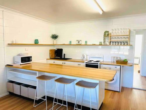 a kitchen with a wooden counter top and stools at Brooms Beach Stay in Brooms Head