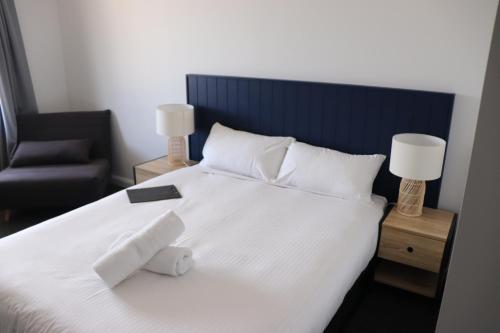 um quarto com uma cama branca com uma cadeira e candeeiros em The Anglers Inn em Wallaroo