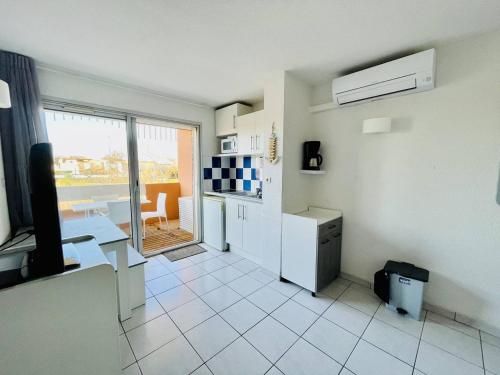 - une cuisine blanche avec une table et un comptoir dans l'établissement Appartement avec Piscine, Climatisation, et Parking à 2 Pas de la Plage - FR-1-723-133, au Cap d'Agde