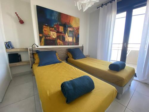 2 camas en una habitación con sábanas amarillas y almohadas azules en Appartement Canet-Plage, 3 pièces, 4 personnes - FR-1-750-61, en Canet-en-Roussillon