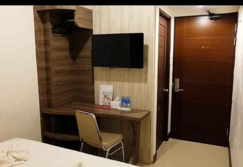 Zimmer mit einem Schreibtisch mit Stuhl und einem TV in der Unterkunft HOTEL MY HOME in Sintang