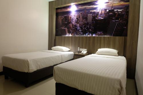 Sintang的住宿－HOTEL MY HOME，两张位于酒店客房的床,墙上挂着照片