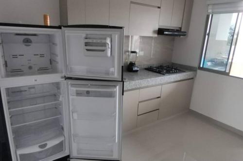 Il comprend une cuisine blanche équipée d'un réfrigérateur et d'une cuisinière. dans l'établissement Apartamento Amueblados Jireh, à San Onofre
