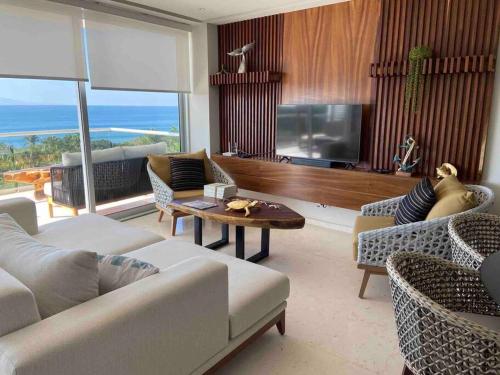 un soggiorno con un divano, una TV e un tavolo di Increíble departamento en Bolongo punta de mita a Higuera Blanca