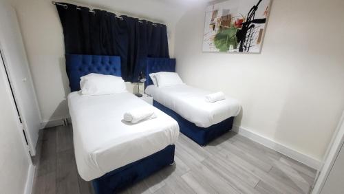 two beds in a room with blue and white at Garland Modern Close To Station 3 Bedroom City Apartment in London