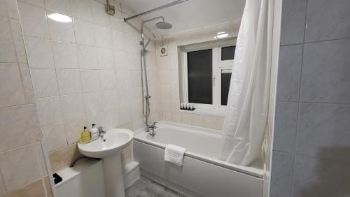 a white bathroom with a sink and a tub and a sink at Garland Modern Close To Station 3 Bedroom City Apartment in London