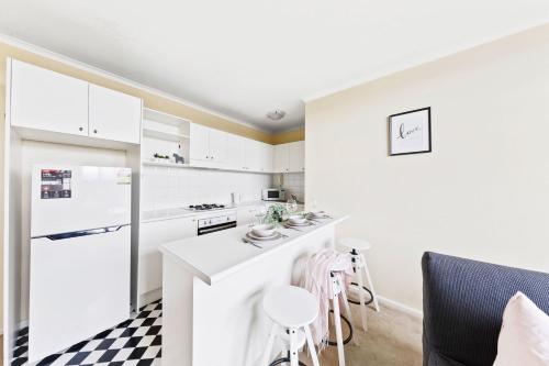 a kitchen with white cabinets and a black and white checkered floor at A Comfy & Cozy Apt in Clifton Hill FREE Parking in Melbourne