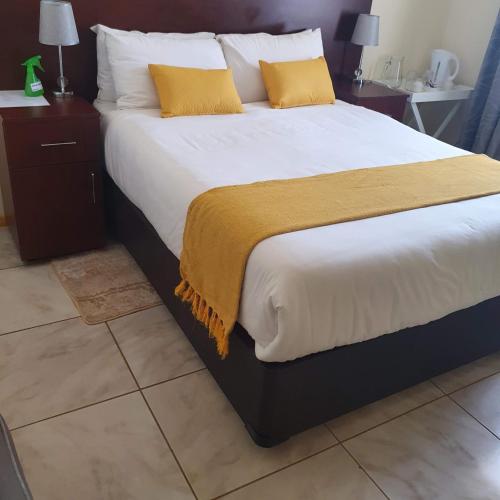 ein großes Bett mit weißer Bettwäsche und gelben Kissen in der Unterkunft Thokgamo Bed and Breakfast in Kanye