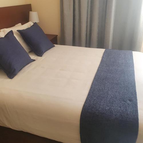 a large white bed with blue pillows in a room at Thokgamo Bed and Breakfast in Kanye