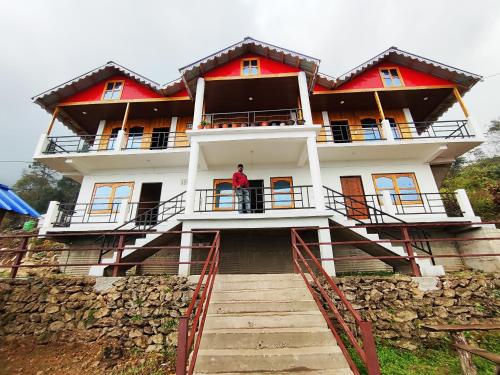 a man standing on the balcony of a house at Mount View Homestay Sittong in Mangpu