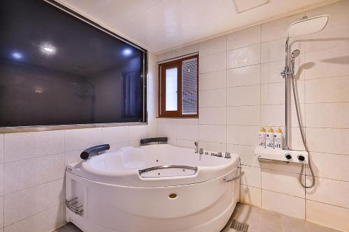 a white bathroom with a tub and a shower at Flower Hotel in Seoul