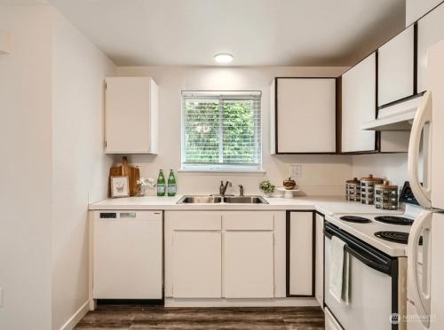 タコマにあるCharming 2 Bedroom in Tacomaの白いキャビネットとシンクのあるキッチン