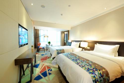 um quarto de hotel com duas camas e uma televisão de ecrã plano em Chao Man Hotel - Guangzhou Railway Station Sanyuanli Metro Station em Guangzhou