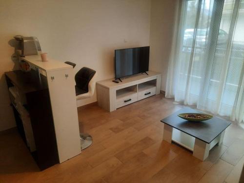 a living room with a flat screen tv and a table at studio à proximité de Genève in Étrembières