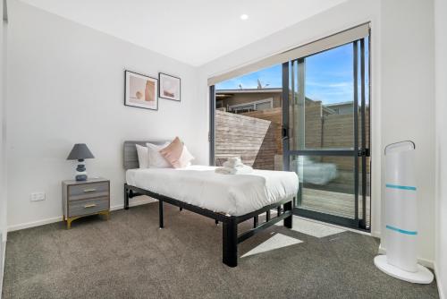 een slaapkamer met een bed en een glazen schuifdeur bij Your home away from home located near Auckland CBD in Auckland