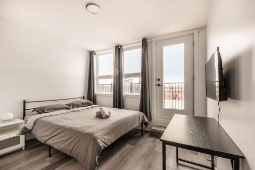 a bedroom with a bed and a tv and windows at Cozy 2 bedroom apartment on 2 floors - 1107 in Montreal