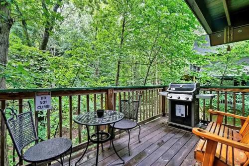 a deck with a table and chairs and a grill at Cozy Cabin, Sleeps 8 - Close to Dollywood with Hot Tub, Arcade, Community Pool in Pigeon Forge