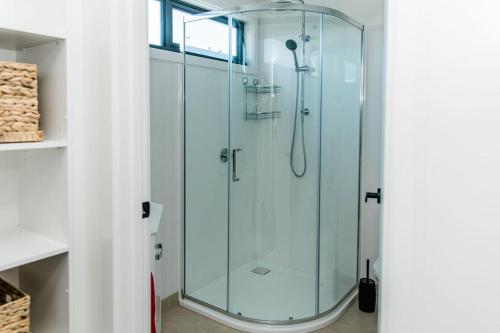 een glazen douche in een badkamer met witte muren bij The Nest Beach Getaway in Torquay