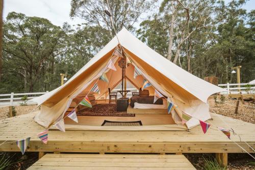 Zelt mit einem Bett auf einer Holzterrasse in der Unterkunft The Woods Farm Jervis Bay in Tomerong