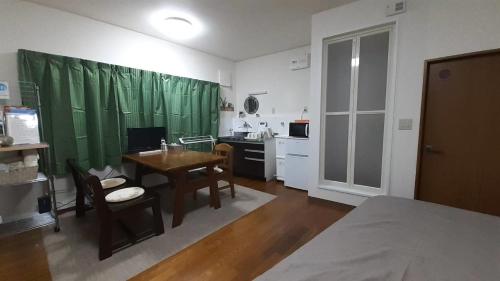 Habitación con mesa y cocina con cortinas verdes en Noah House 102貸切, en Shingu