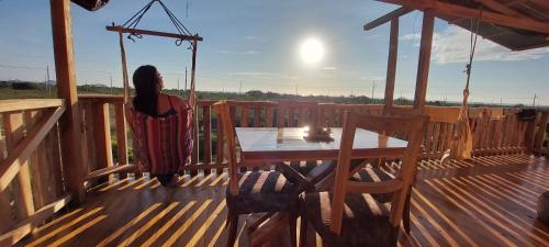 uma mulher de pé num convés com uma mesa em House Beach em Puerto Cayo