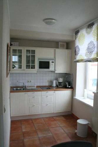 uma cozinha com armários brancos, um lavatório e uma janela em Strandstraße 32 - 04-21 em Kühlungsborn