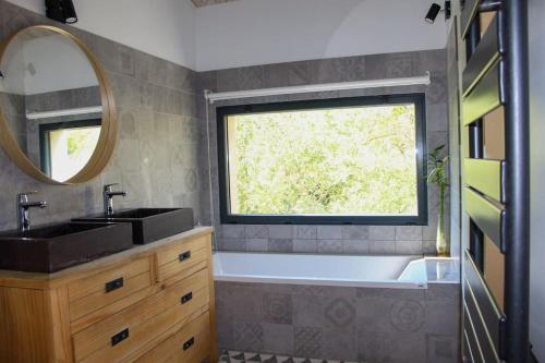 une salle de bain avec une baignoire, un lavabo et une fenêtre dans l'établissement Le Moulin du plô du Roy, à Villeneuve-Minervois