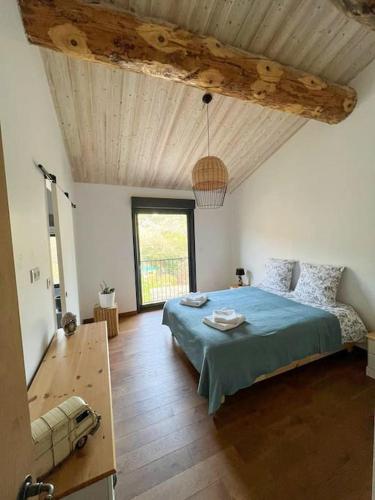 une chambre avec un lit et un plafond en bois dans l'établissement Le Moulin du plô du Roy, à Villeneuve-Minervois